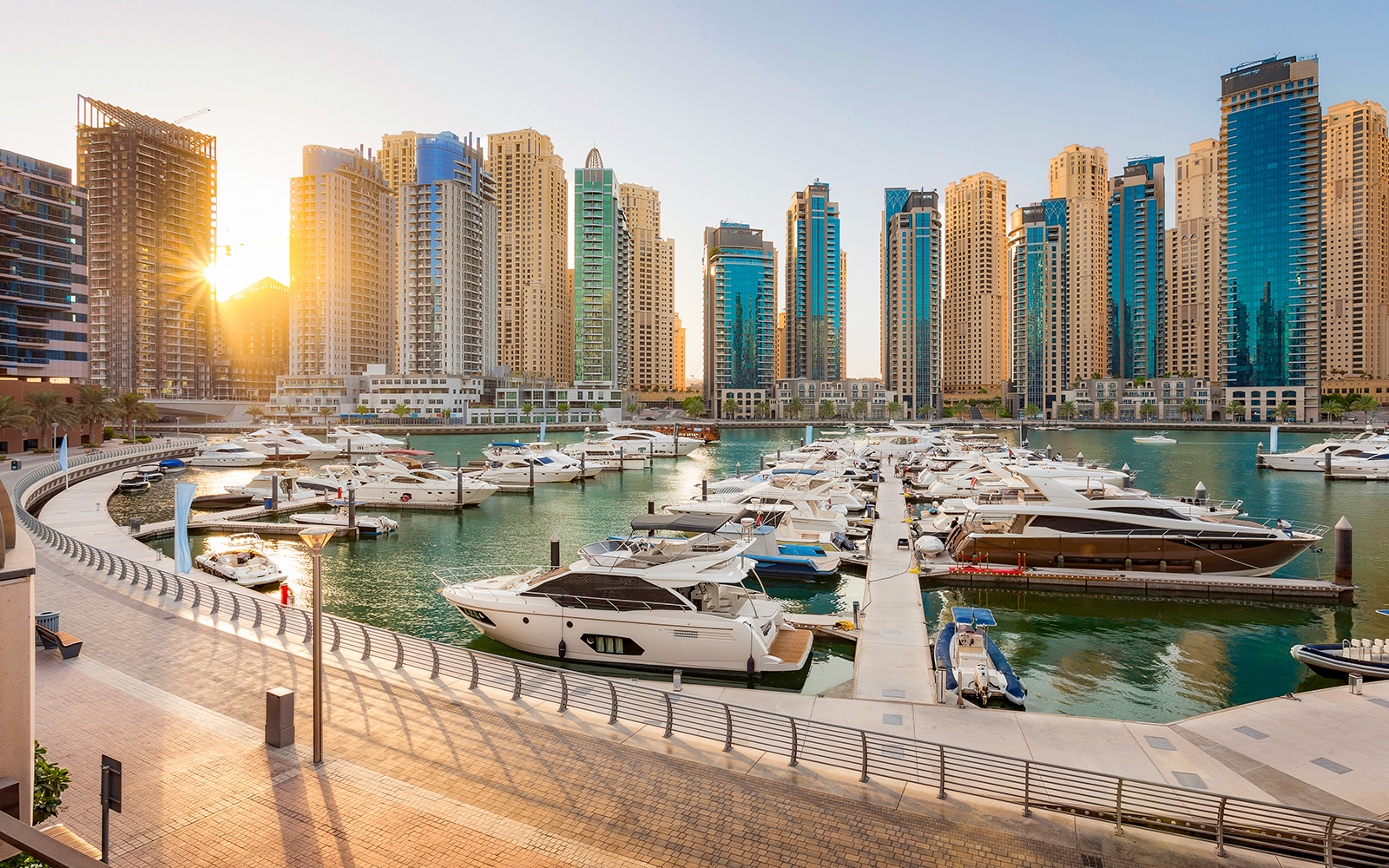 Boats docked at Dubai Marina with skyscrapers in the background.