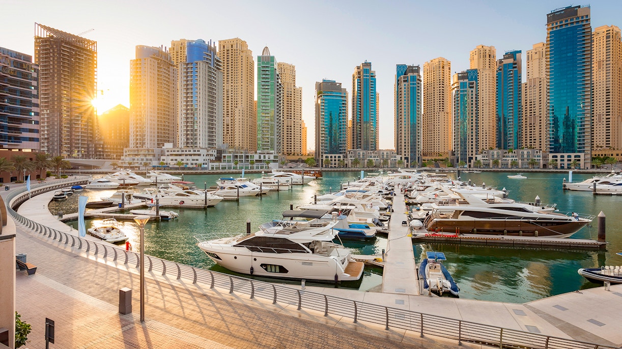 Boats docked at Dubai Marina with skyscrapers in the background.