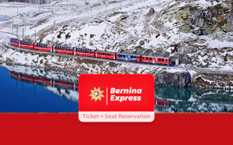Bernina Express train traveling through snowy Alps near a reflective lake, Tirano to St. Moritz route.