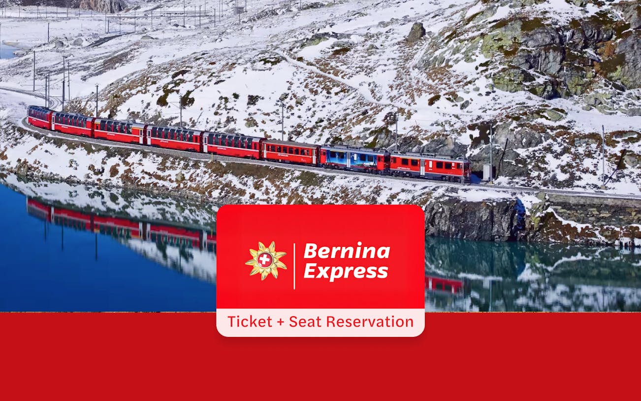 Bernina Express train traveling through snowy Alps near a reflective lake, Tirano to St. Moritz route.