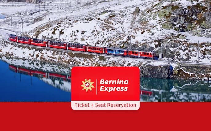 Bernina Express train traveling through snowy Alps near a reflective lake, Tirano to St. Moritz route.