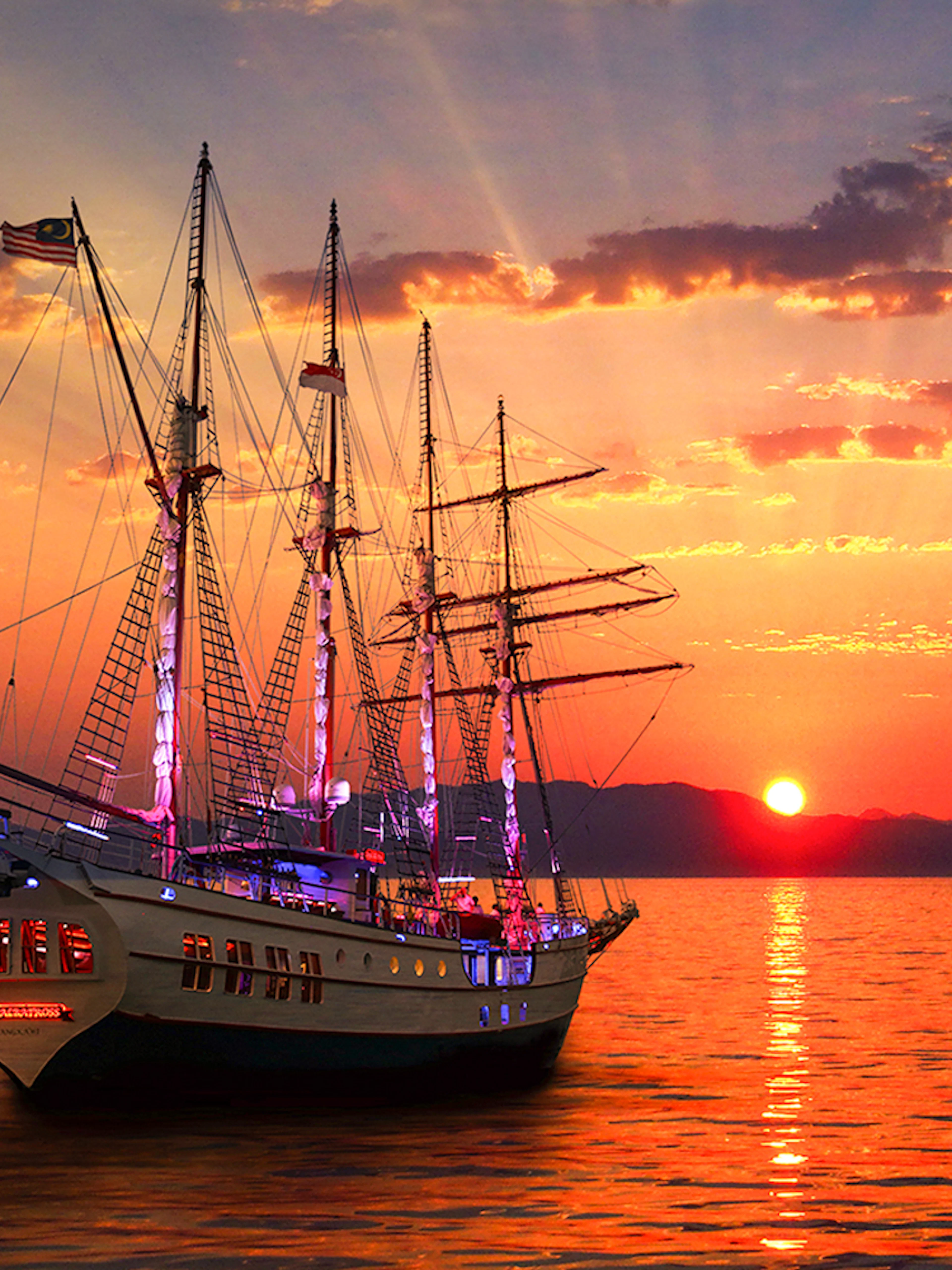 Sunset view of The Royal Albatross sailing on calm waters during a dinner cruise.