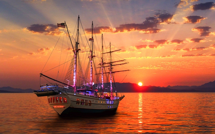Sunset view of The Royal Albatross sailing on calm waters during a dinner cruise.