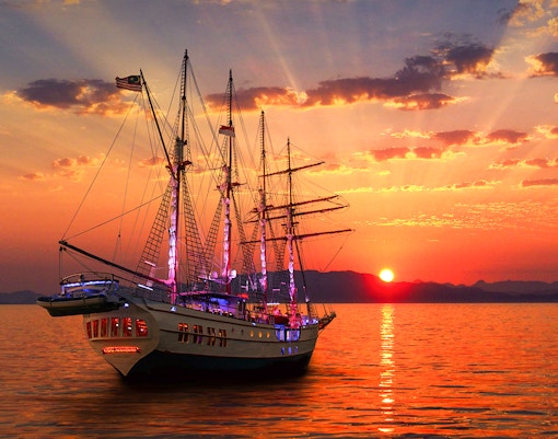 Sunset view of The Royal Albatross sailing on calm waters during a dinner cruise.