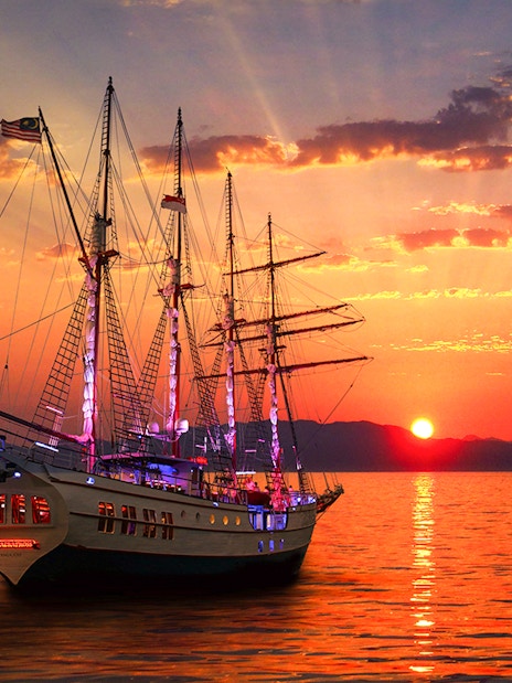 Sunset view of The Royal Albatross sailing on calm waters during a dinner cruise.