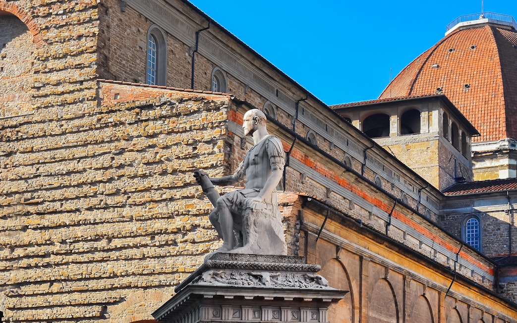 Statue in San Lorenzo Square, Florence, with historic architecture in the background.
