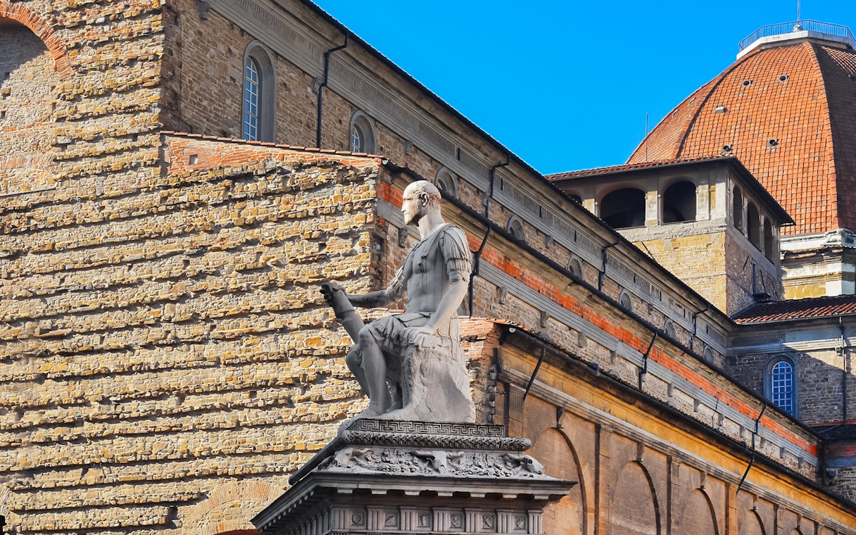 Statue in San Lorenzo Square, Florence, with historic architecture in the background.