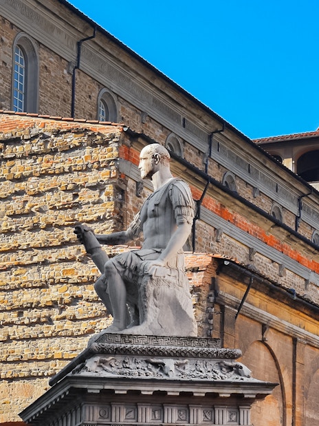 Statue in San Lorenzo Square, Florence, with historic architecture in the background.