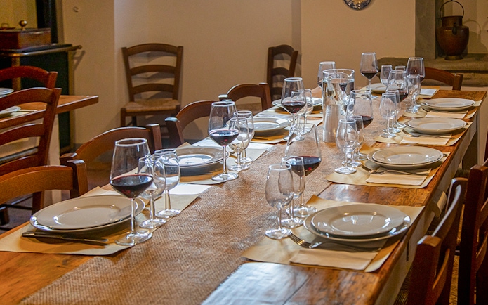 Dining table set with wine glasses and plates for a Tuscany tour experience.