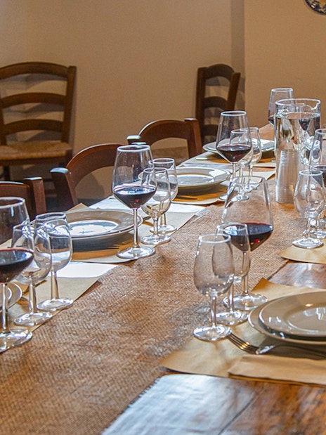 Dining table set with wine glasses and plates for a Tuscany tour experience.