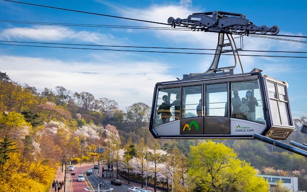 Namsan cable car over scenic spring landscape in Seoul, South Korea.
