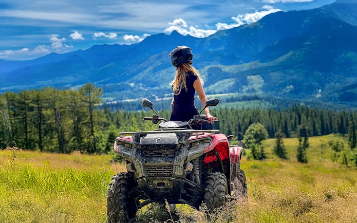 Visitor on quad bike overlooking Zakopane mountains and forest.