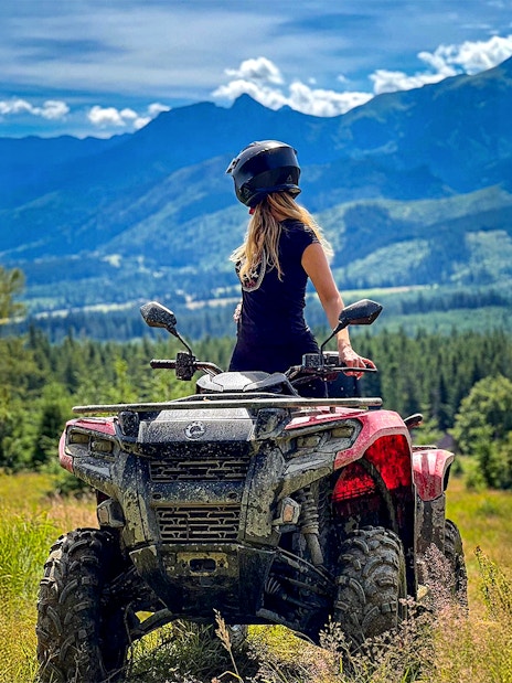 Visitor on quad bike overlooking Zakopane mountains and forest.