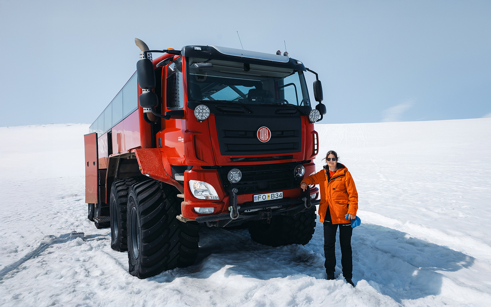 Red Monster truck on Langjökull Glacier tour from Gullfoss with a person standing beside it.
