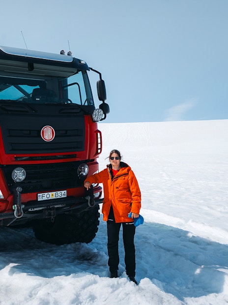Red Monster truck on Langjökull Glacier tour from Gullfoss with a person standing beside it.
