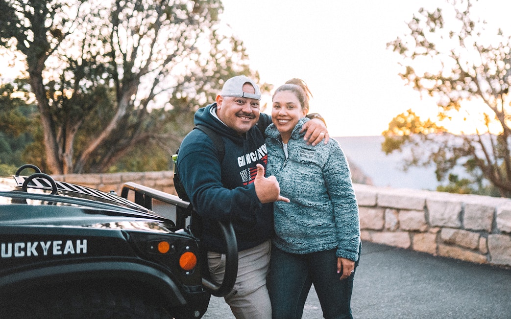 Tourists posing by a jeep on a Grand Canyon guided tour.