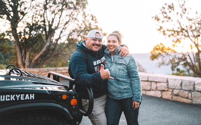 Tourists posing by a jeep on a Grand Canyon guided tour.