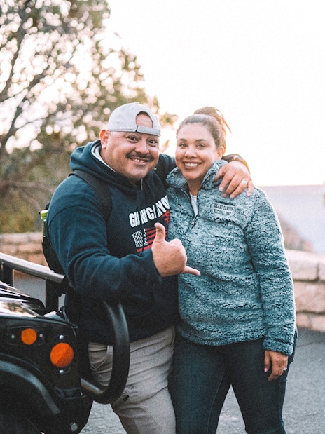 Tourists posing by a jeep on a Grand Canyon guided tour.
