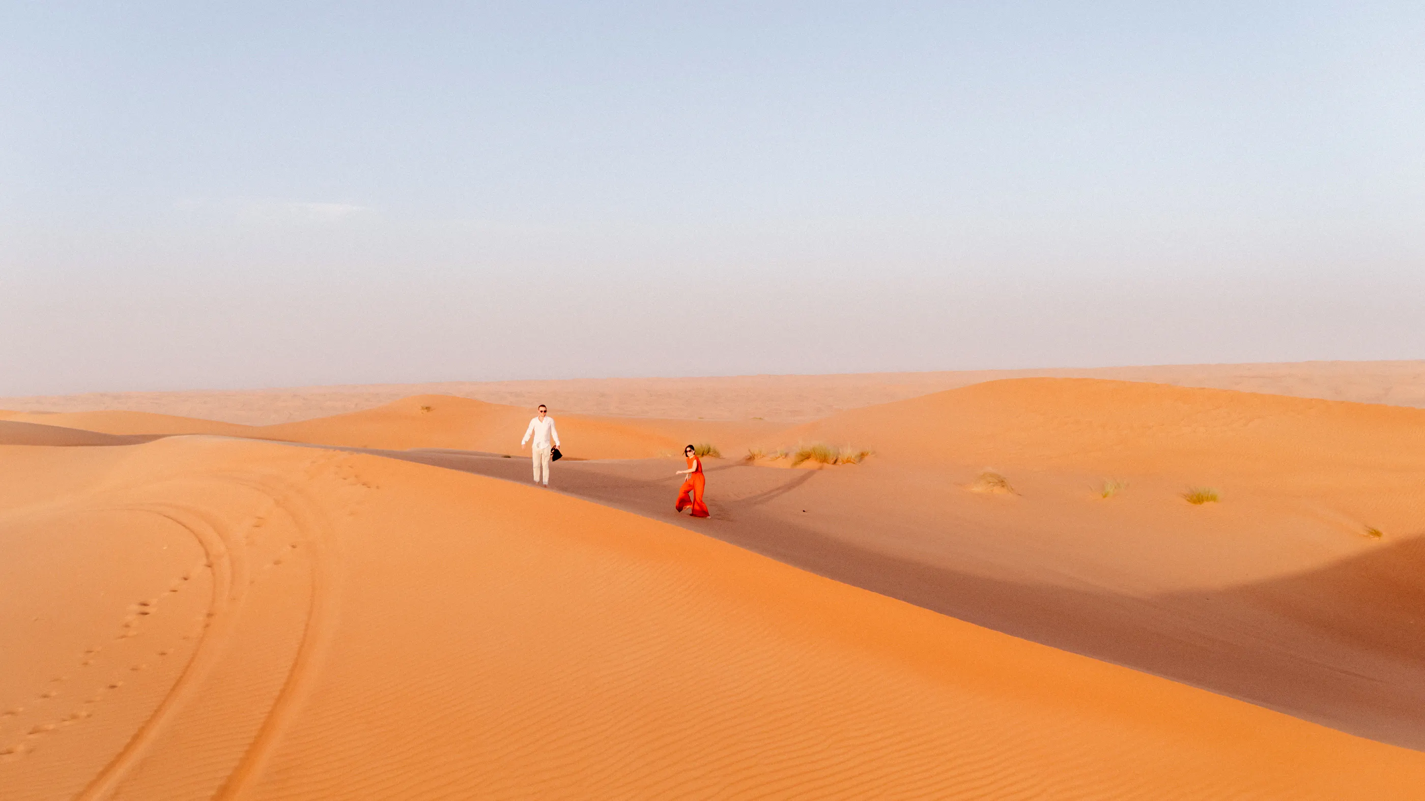 Couple walking on sand dunes in Wahiba Desert during guided tour, Muscat.