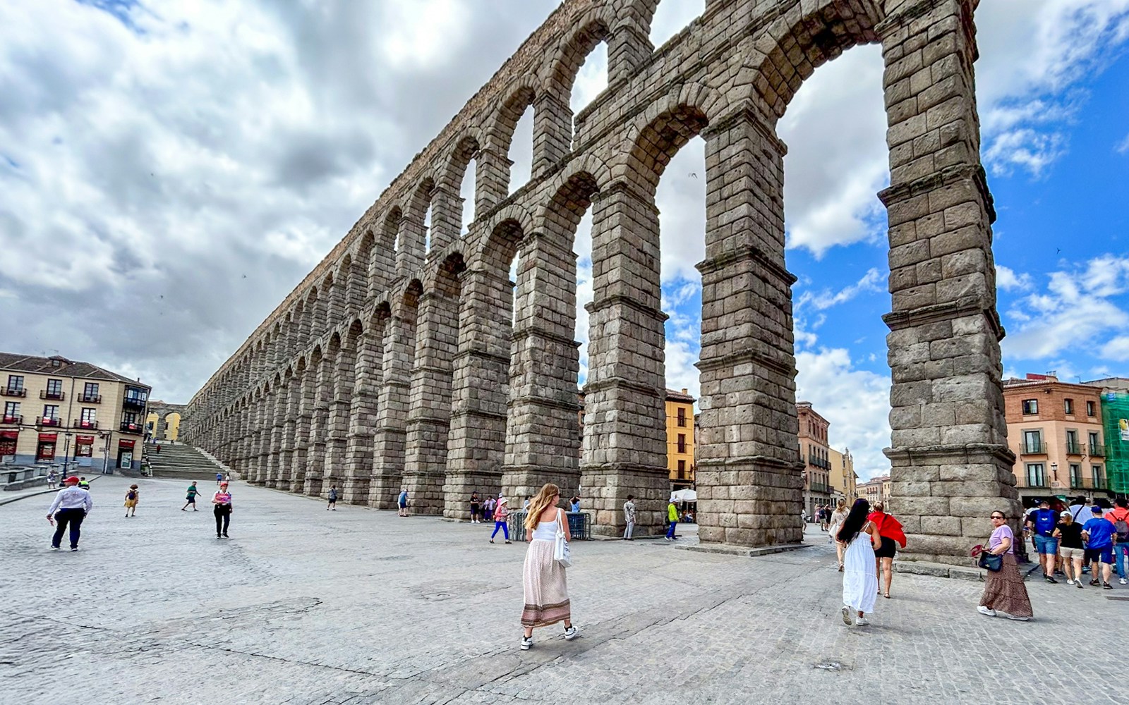 Tourists walking near the ancient Segovia Aqueduct in Spain.