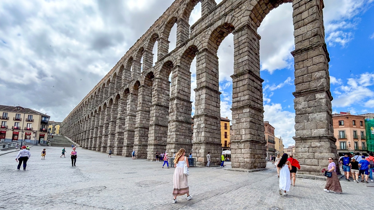 Segovia Aqueduct with tourists walking nearby, Spain.
