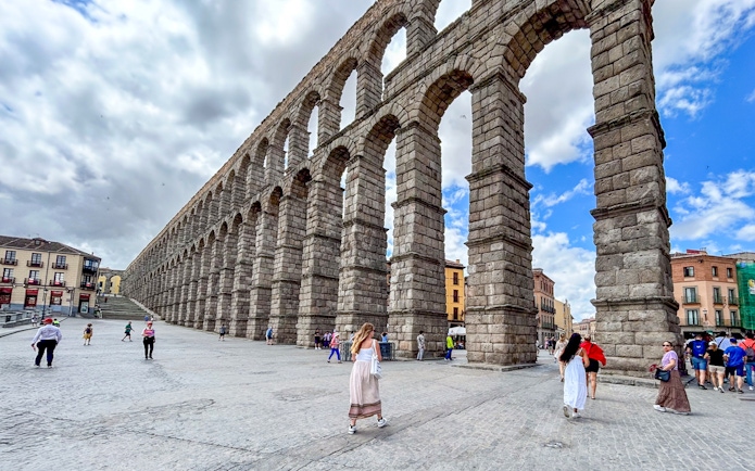 Segovia Aqueduct with tourists walking nearby, Spain.