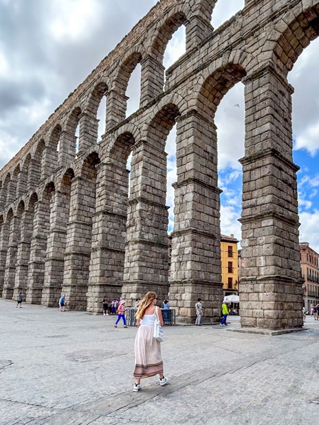Segovia Aqueduct with tourists walking nearby, Spain.