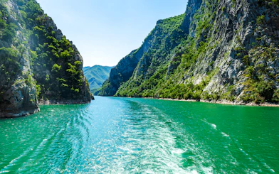 Komani Lake view with surrounding green cliffs during Tirana tour.