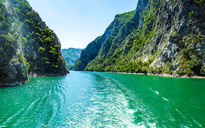 Komani Lake view with surrounding green cliffs during Tirana tour.