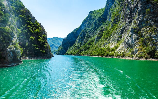 Komani Lake view with surrounding green cliffs during Tirana tour.