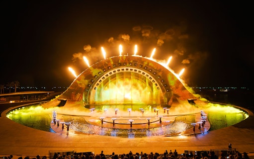 Performers with fire effects at Kiss of the Sea Show, vibrant stage lighting.