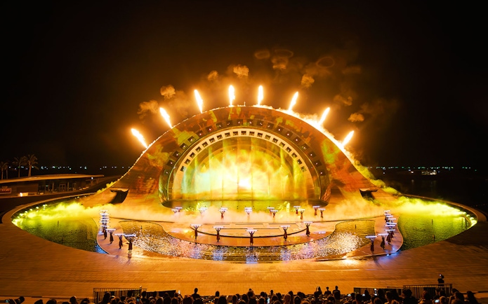 Performers with fire effects at Kiss of the Sea Show, vibrant stage lighting.