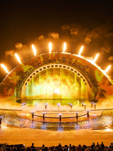 Performers with fire effects at Kiss of the Sea Show, vibrant stage lighting.