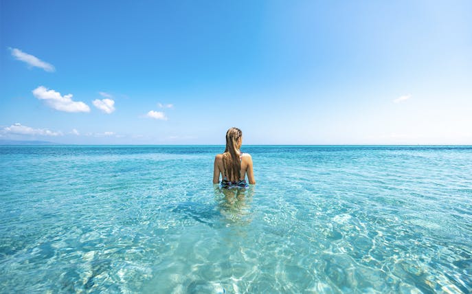 Person standing in clear blue water at Cala Mariolu during guided boat tour.