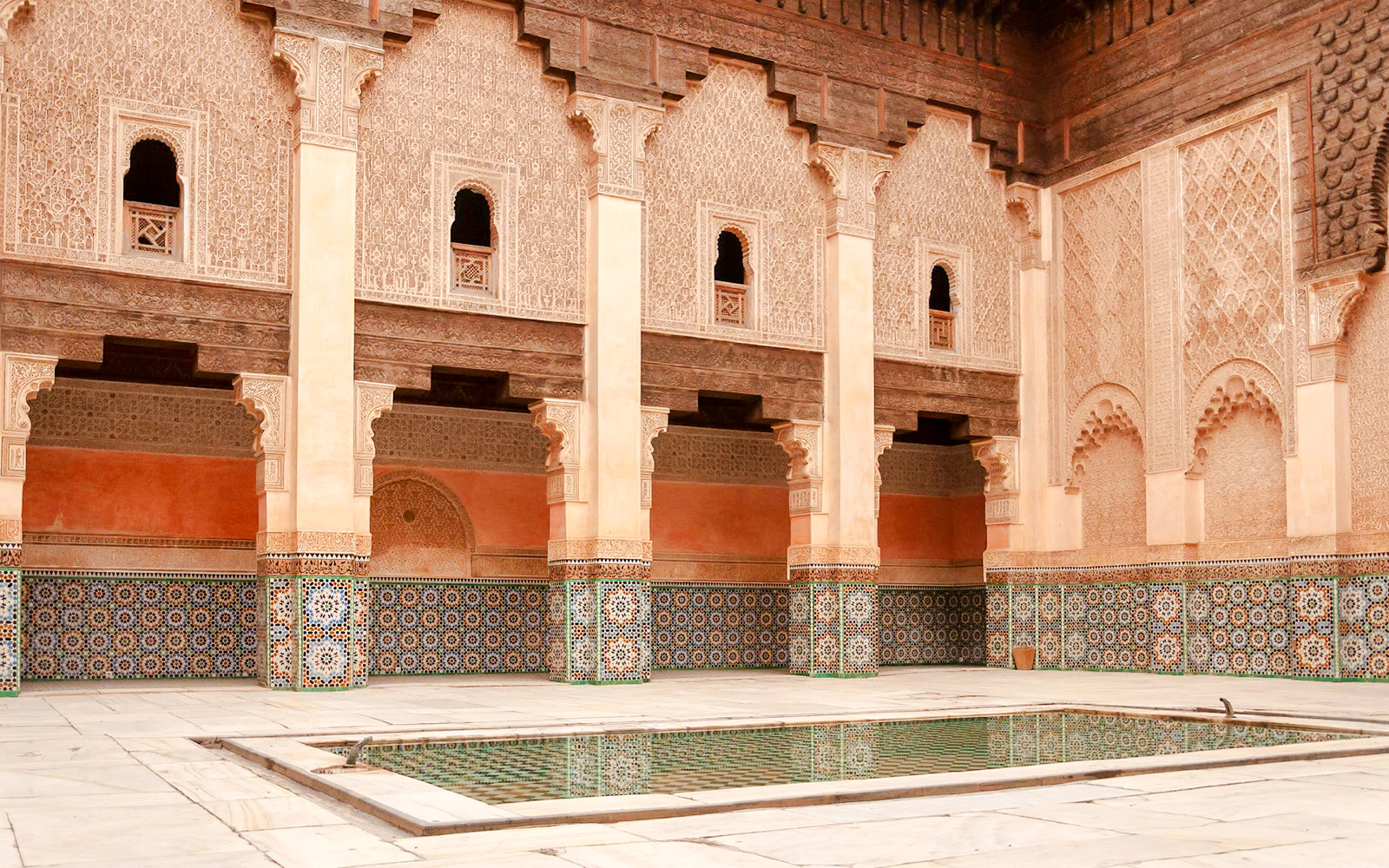 Madrasa Ben Youssef courtyard with intricate tilework and arches in Marrakech, Morocco.