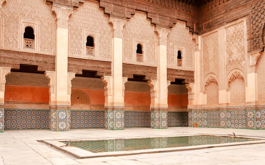 Madrasa Ben Youssef courtyard with intricate tilework and arches in Marrakech, Morocco.