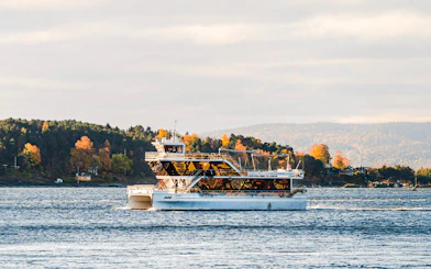 Silent fjord cruise boat on Oslofjord with autumn trees in the background.