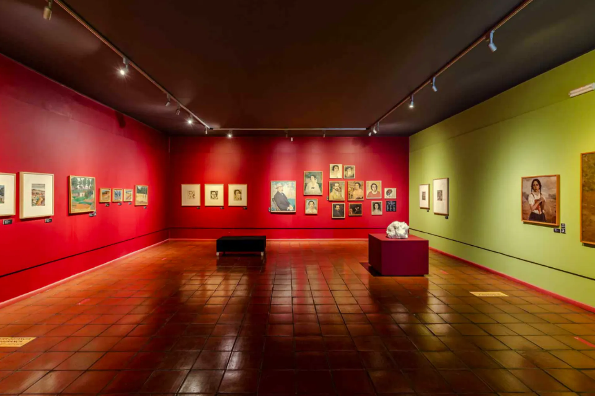 Art gallery interior with paintings on red and green walls, part of Madeira City Pass attractions.