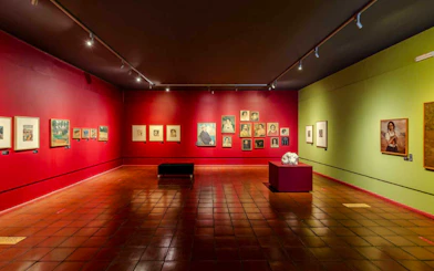 Art gallery interior with paintings on red and green walls, part of Madeira City Pass attractions.