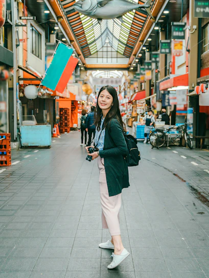 Person exploring Kuromon Ichiba Market in Osaka, surrounded by shops and lanterns.