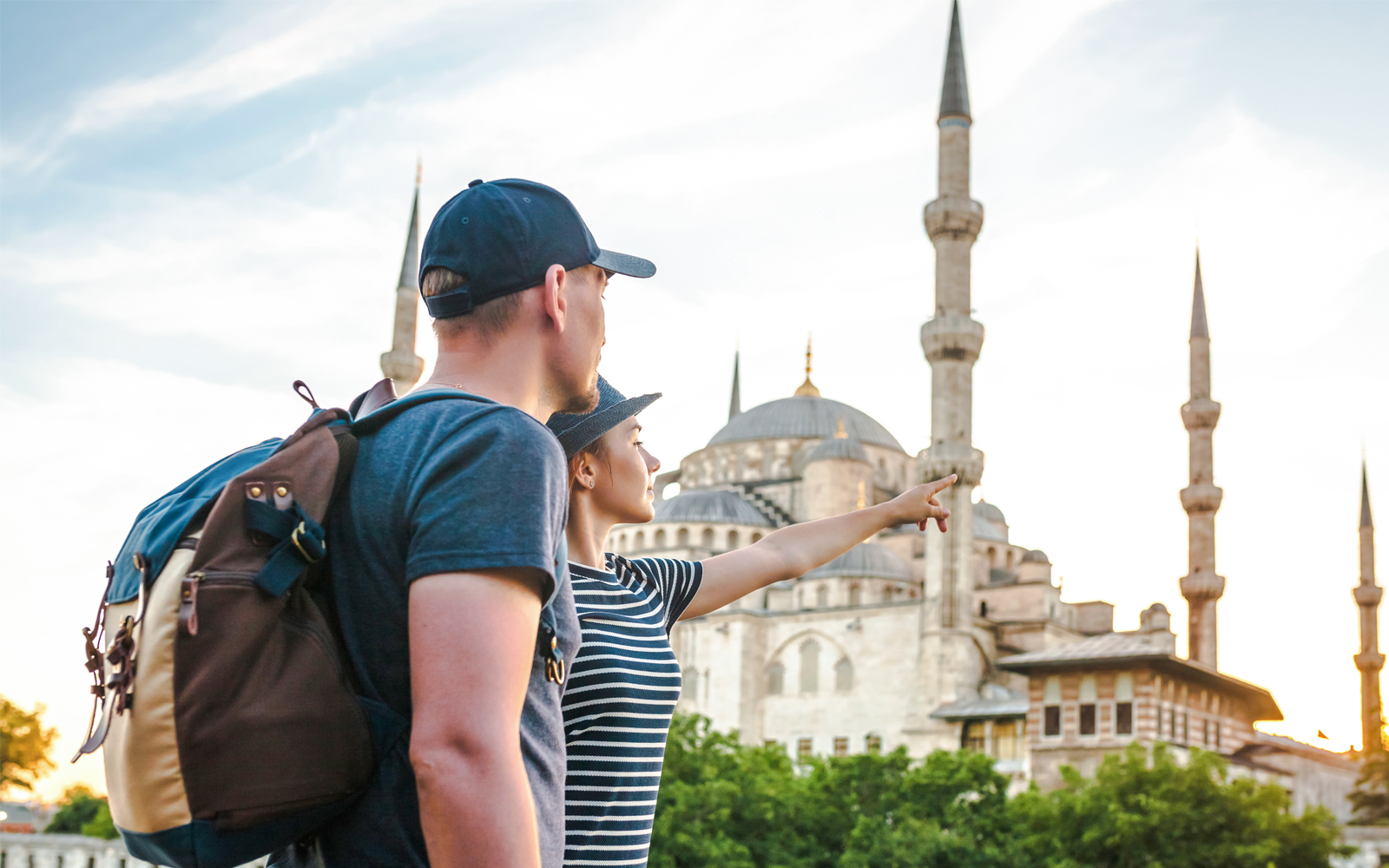 Travelers near the Blue Mosque in Istanbul, Turkey, one pointing towards the landmark.