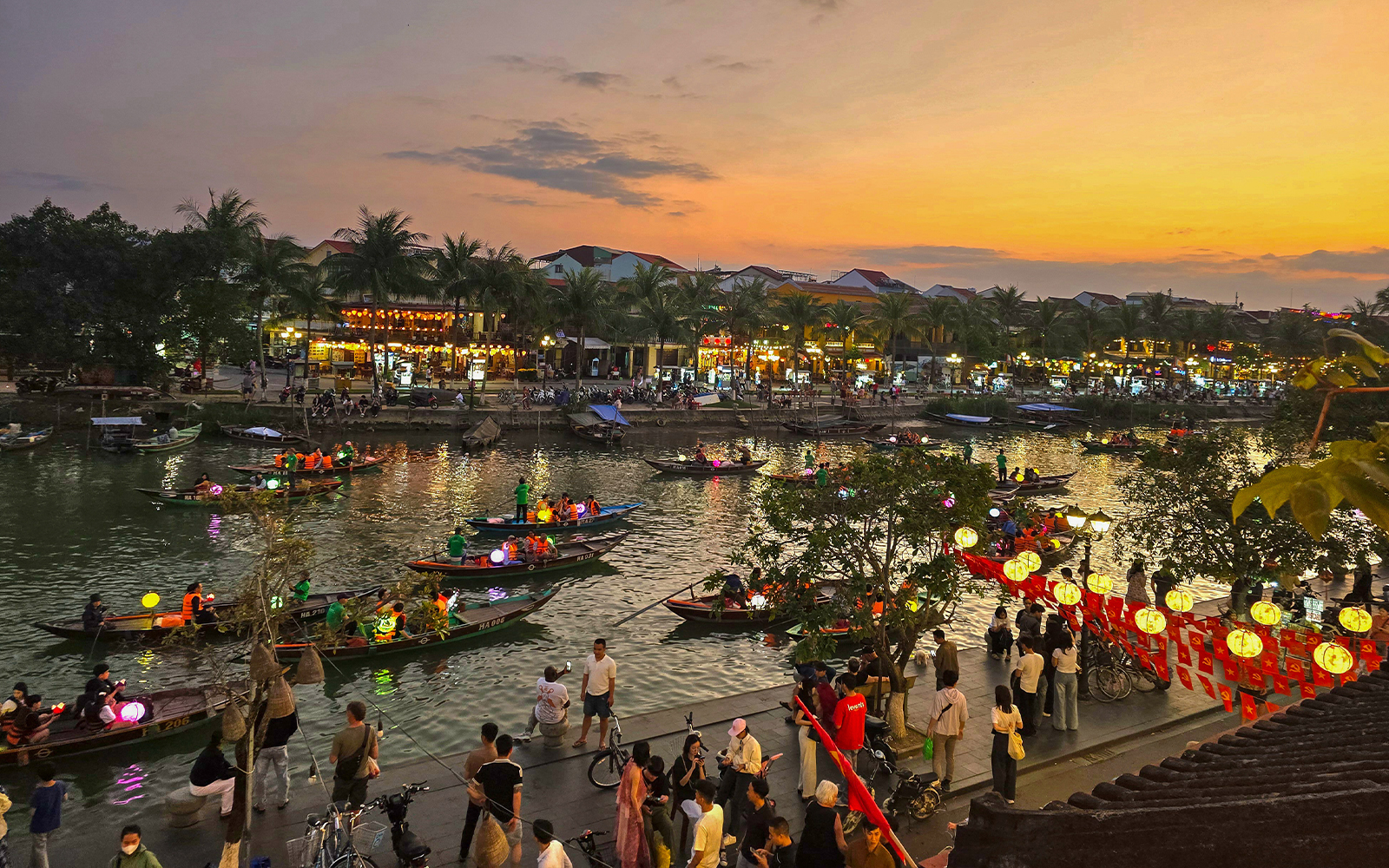 Hoi An river night market with lantern-lit boats and bustling riverside activity.