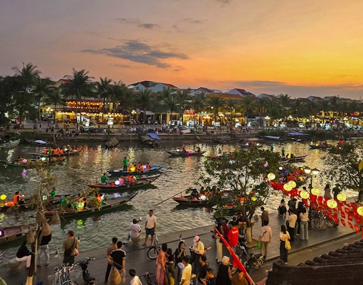 Hoi An river night market with lantern-lit boats and bustling riverside activity.