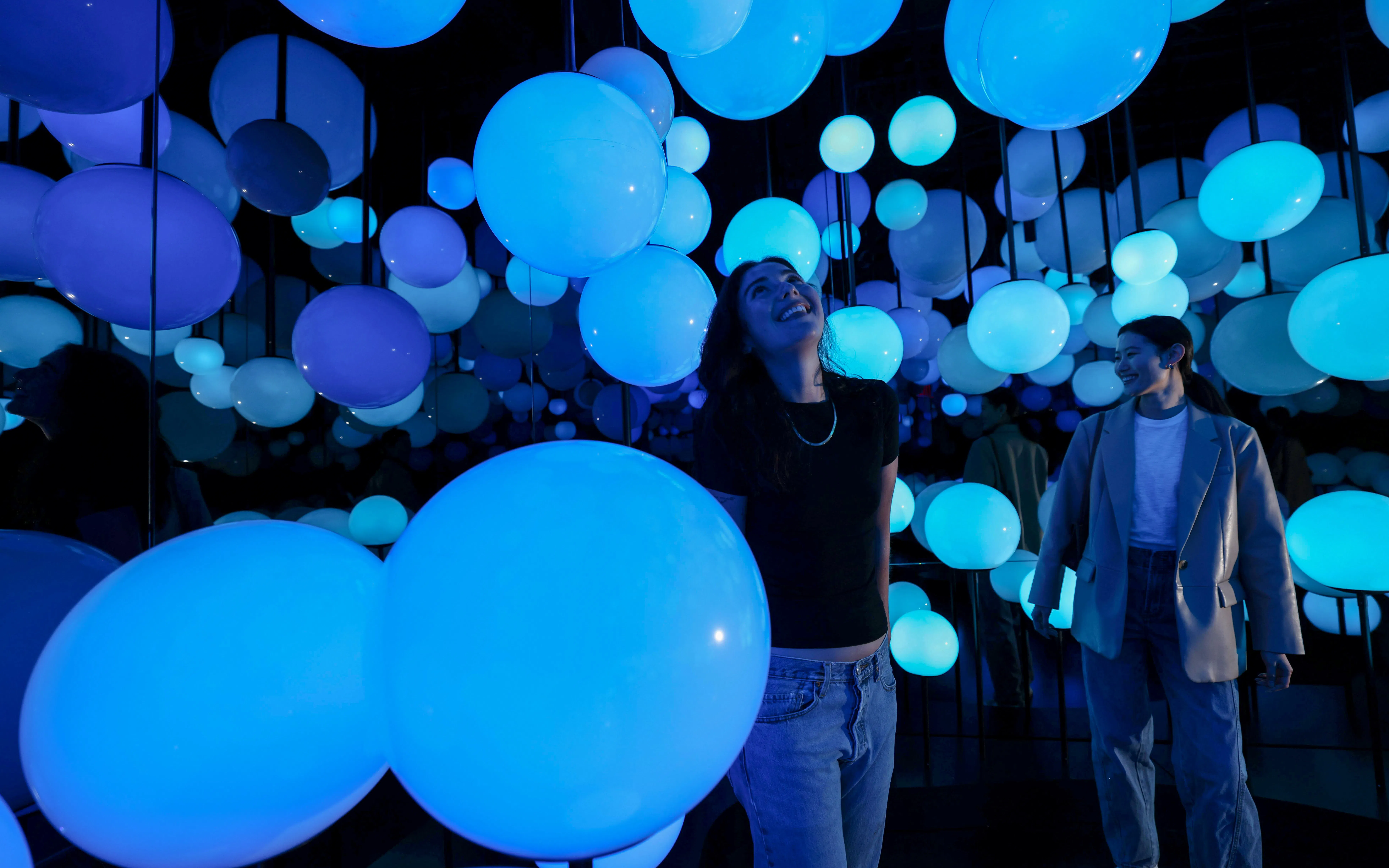 Visitors enjoying illuminated blue spheres at Edge Observatory, New York.