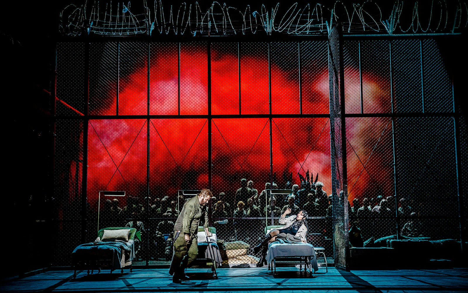 Stage scene from La Forza del Destino with actors in front of a dramatic red backdrop.