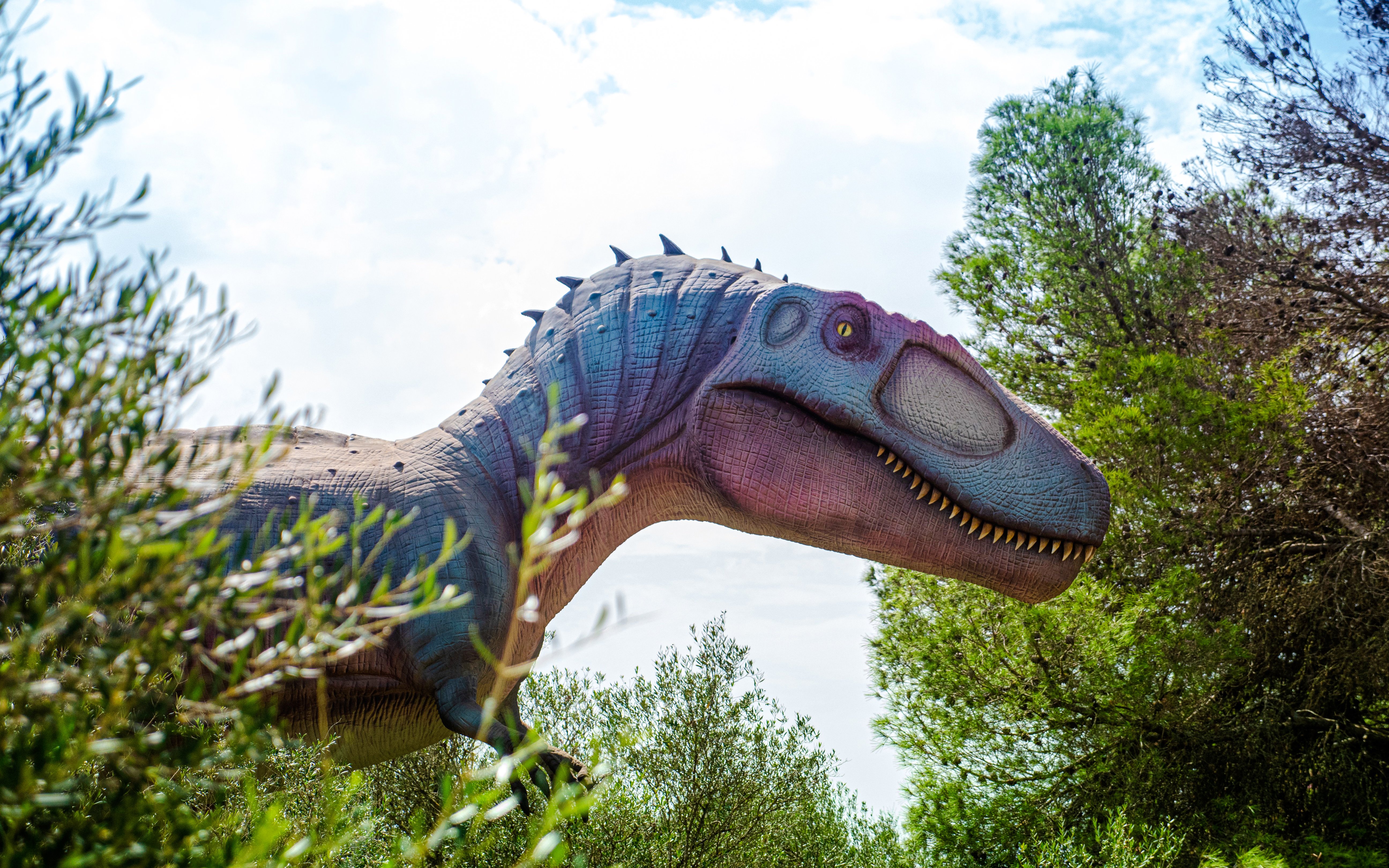 Dinosaur sculpture surrounded by trees at Dinosaurland in Mallorca.