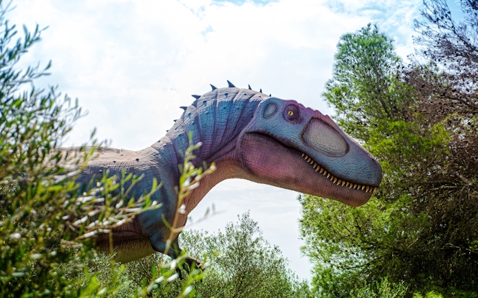 Dinosaur sculpture surrounded by trees at Dinosaurland in Mallorca.