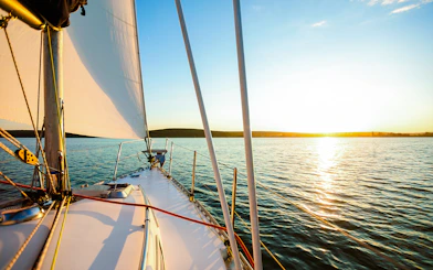 White sailboat on Lisbon waters at sunset.