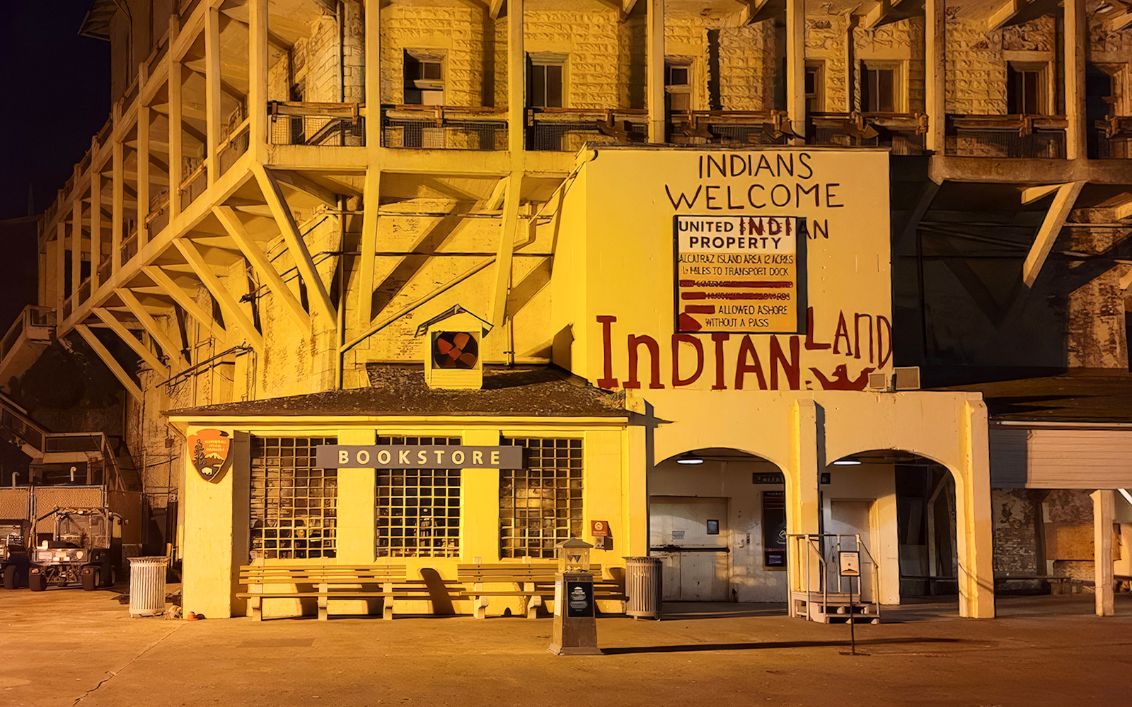 Alcatraz Island bookstore and historic "Indians Welcome" sign at night during ferry tour.
