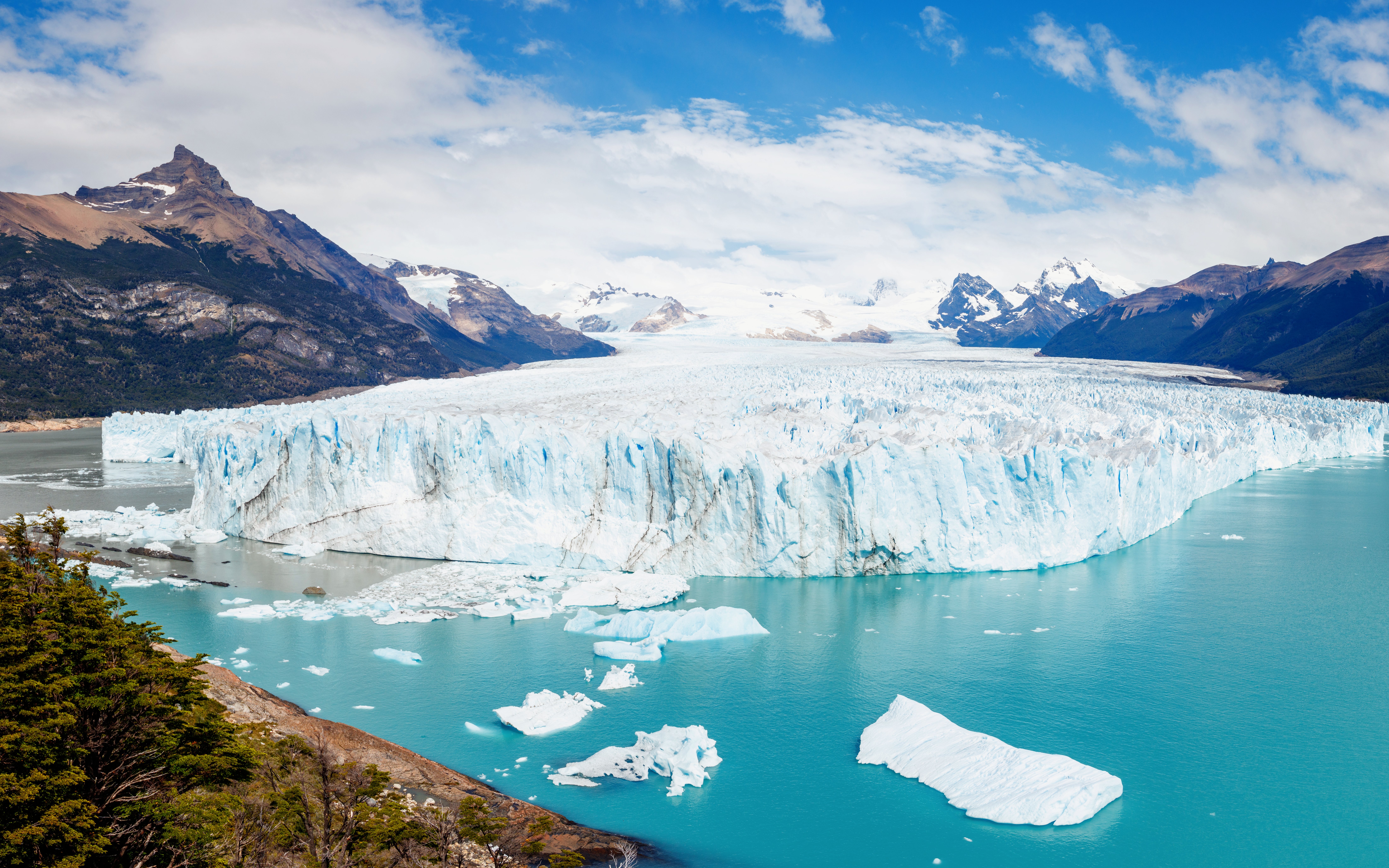 Panoramic view of Perito Moreno Glacier with icebergs and mountains in Los Glaciares National Park, Argentina.
